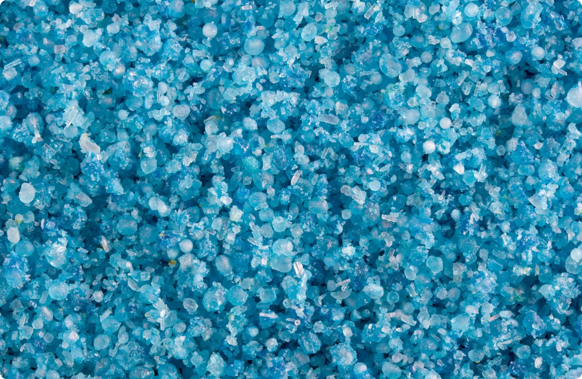Close-up of blue Technigro granular fertilizer crystals showing varied round and angular granules for nutrient release