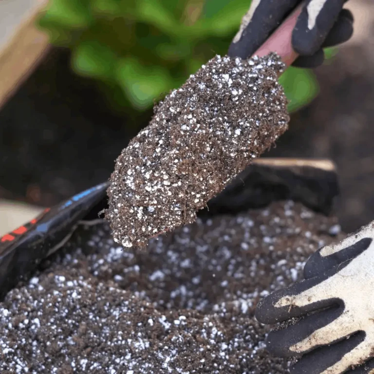 Gloved hands scooping peat-based potting mix with perlite on a trowel over a planting container for home gardening