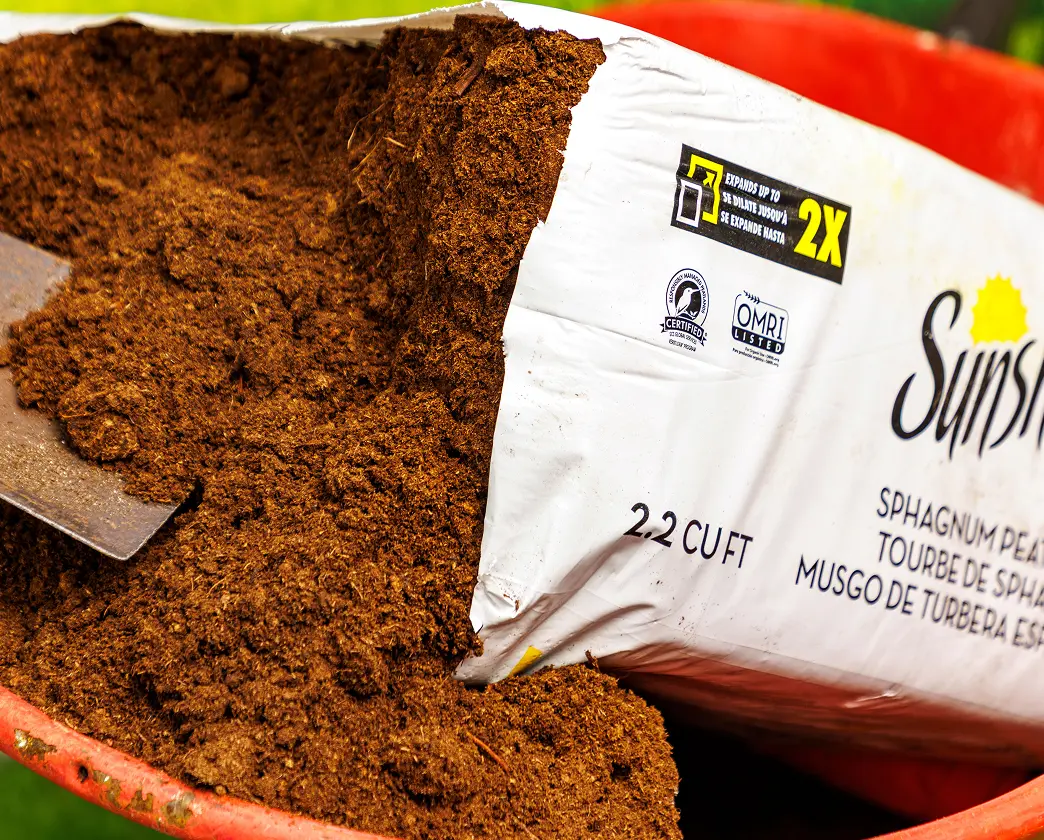 Sunshine potting soil mix bag next to a pile of brown soil mixture.