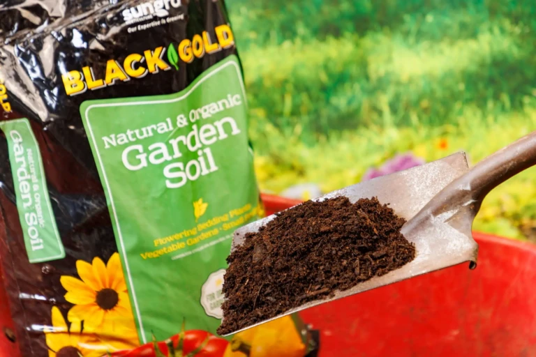 Shovel heaping rich Black Gold natural & organic garden soil in front of Green 